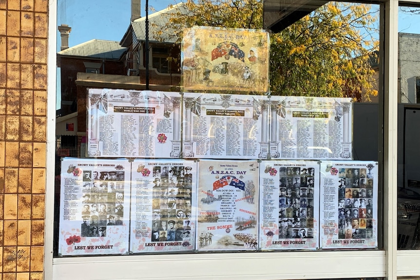 Multiple pages sharing local war history sit behind glass in a Tumut shopfront