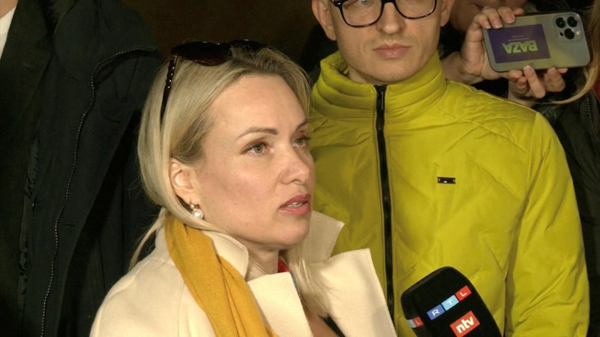 Marina Ovsyannikova is being interviewed by someone holding a microphone to her while she speaks.