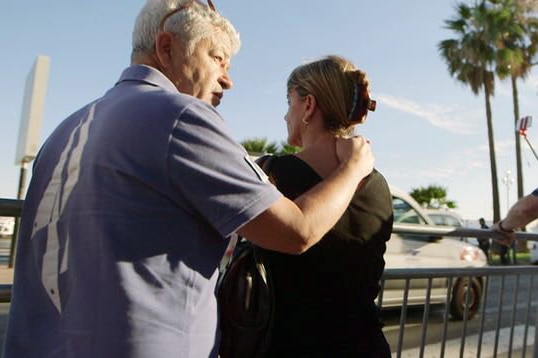 On the Promenade des Anglais, a man puts his hand on a womans shoulder.