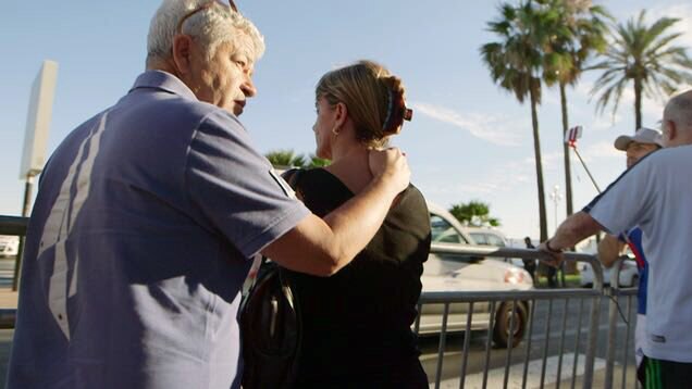 On the Promenade des Anglais, a man puts his hand on a womans shoulder.