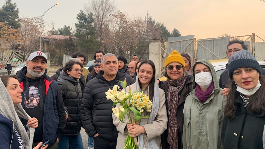 Iranian actress Taraneh Alidoosti holds flowers as she poses for photo among friends.