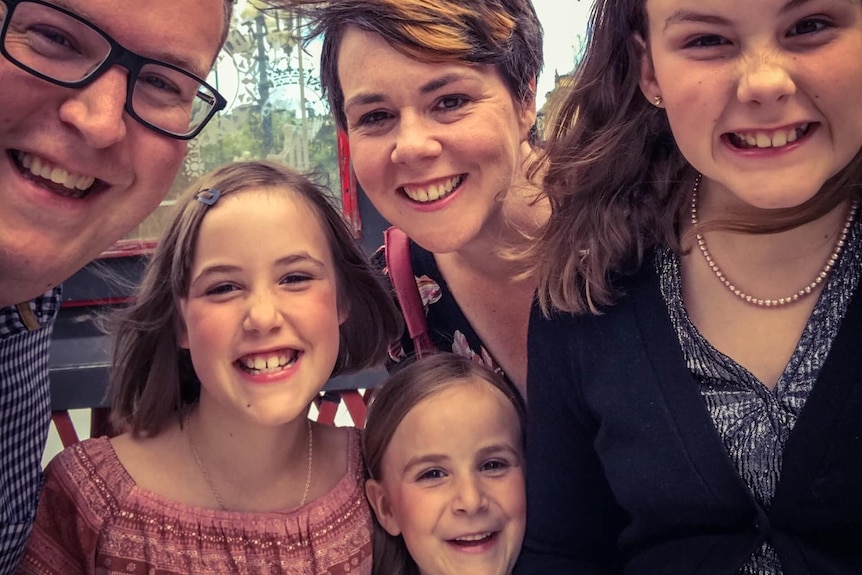 Family of five smile while taking a selfie.