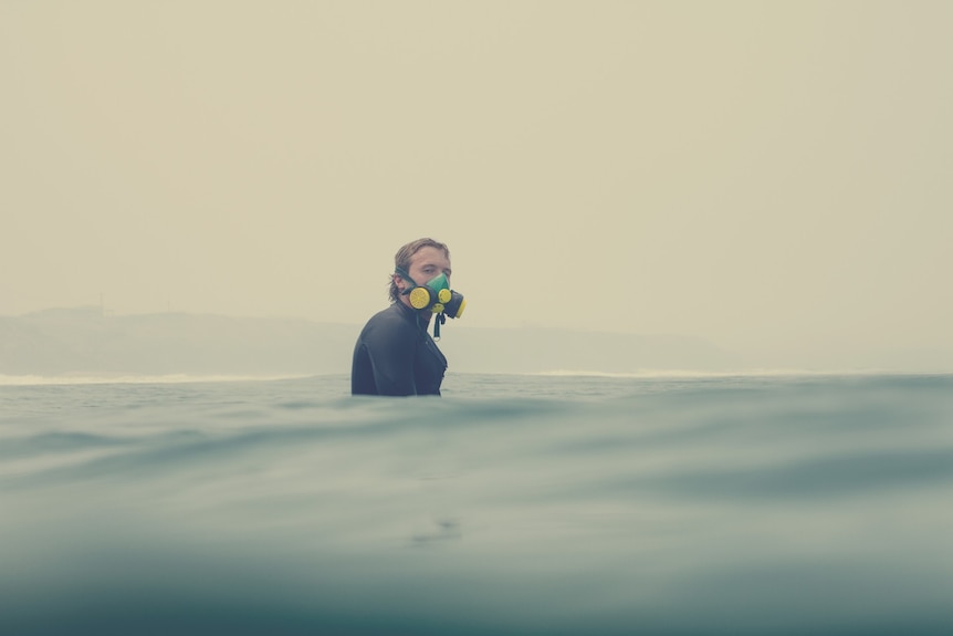 A surfer in the ocean wearing a respirator