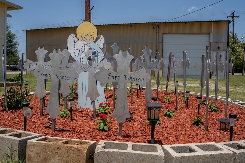 A cardboard blue angel cut-out is set-up next to crosses signifying victims of a mass shooting