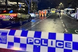 A crime scene with emergency servies pictured on a wet road