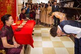 The groom and the bride bowed to their parents in front of a traditional Chinese style setting.