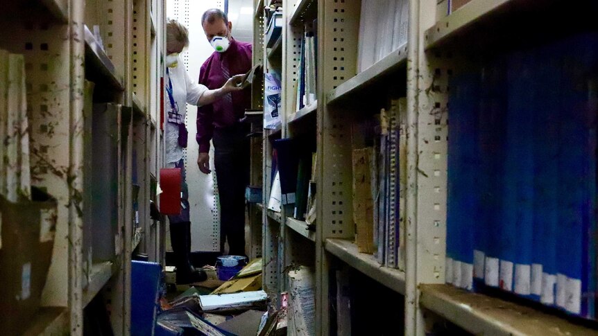 Librarians sort through damaged books still on their shelves.