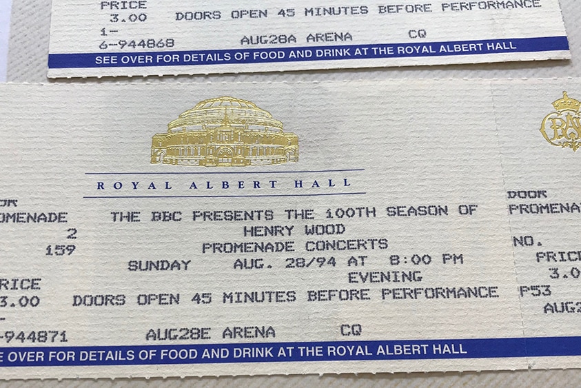 Two old concert tickets with the gold crest of the Royal Albert Hall and a royal blue stripe along the bottom.