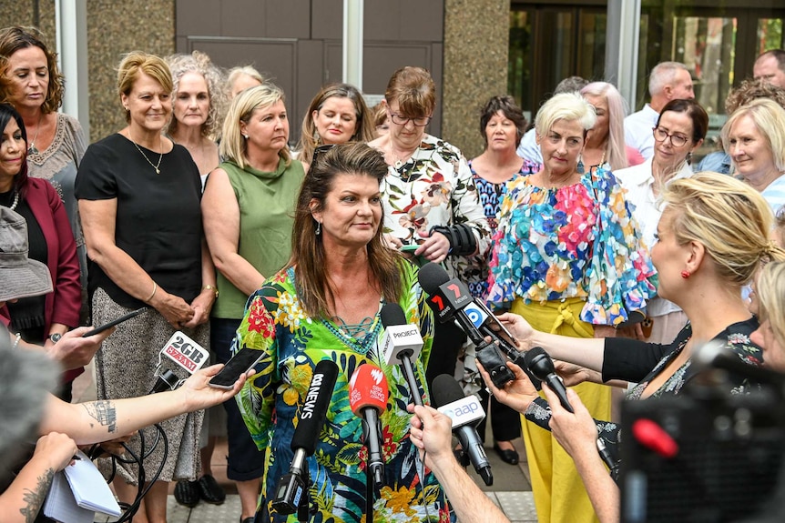 Julie Davis, centre, surrounded by other women involved in the class action suit outside court in Sydney today.