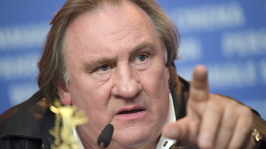 Actor Gerard Depardieu attends a news conference and points his finger at the crowd.
