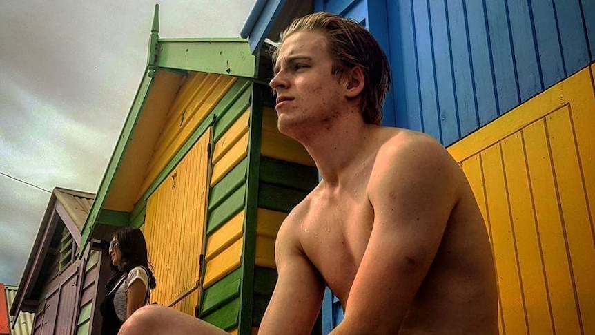 Tom Monagle sitting outside a changing hut at the  beach