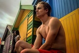 Tom Monagle sitting outside a changing hut at the  beach