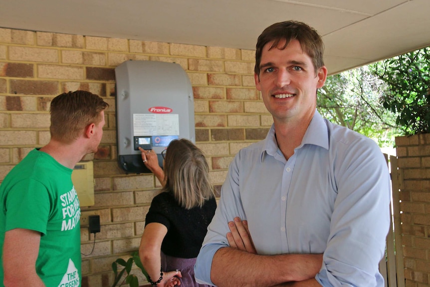 Tim Clifford standing in a garage with a solar battery in the background.