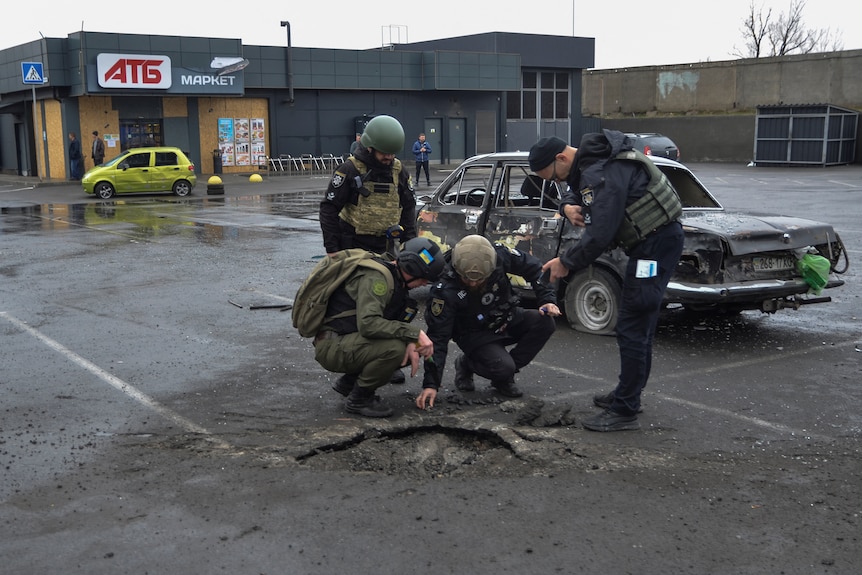 Four people standing around a hole in a car park