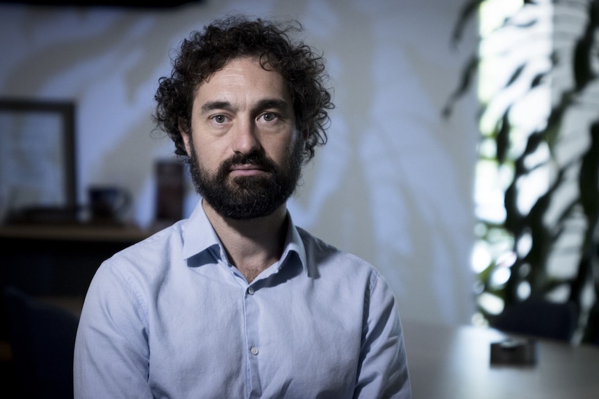 Man with curly hair and beard looks ahead