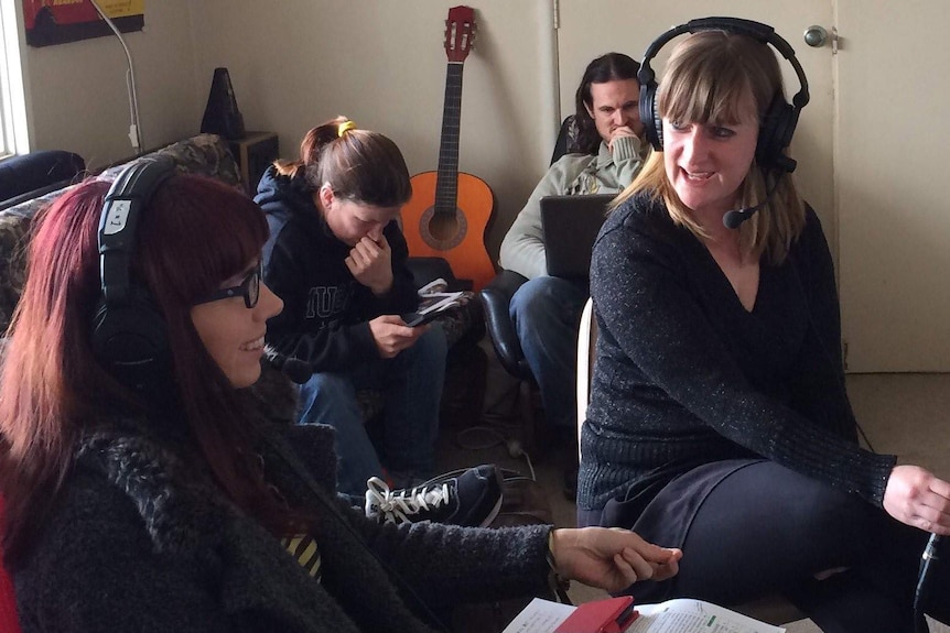 Tight shot of four people sitting in a lounge room.