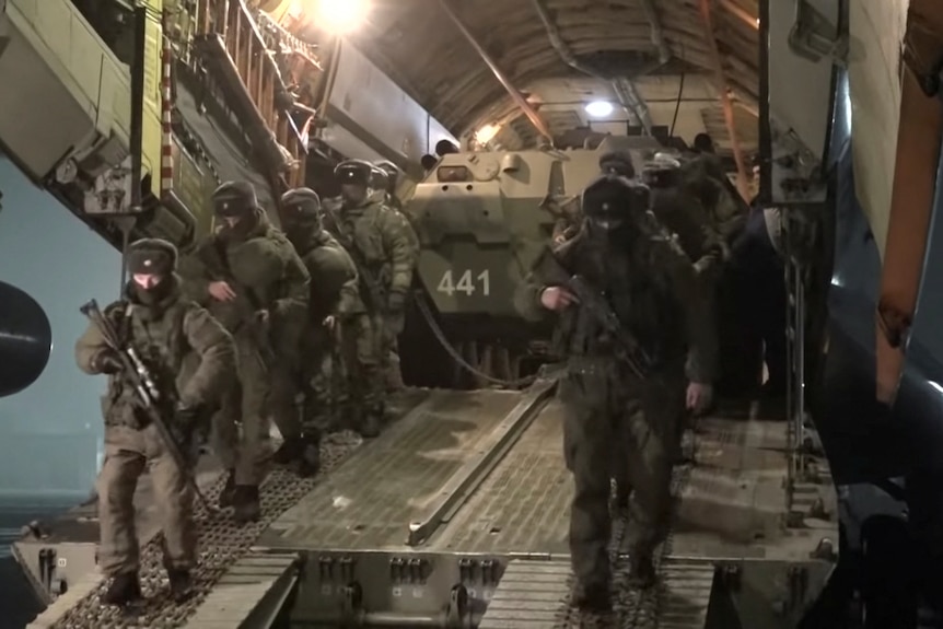 Russian service members disembark from a military aircraft