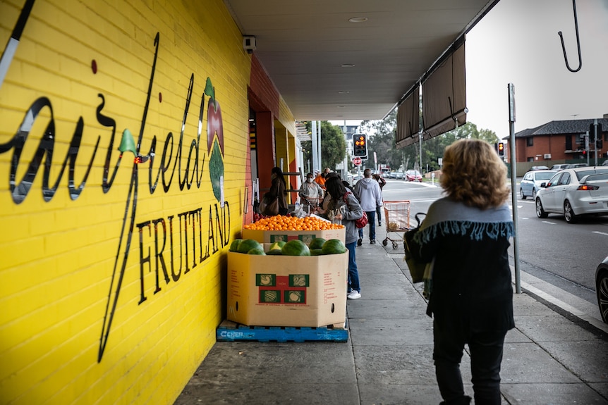 people walking outside a fruit shop