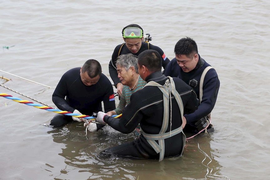 Divers rescue a woman from a sunken ship in Jianli