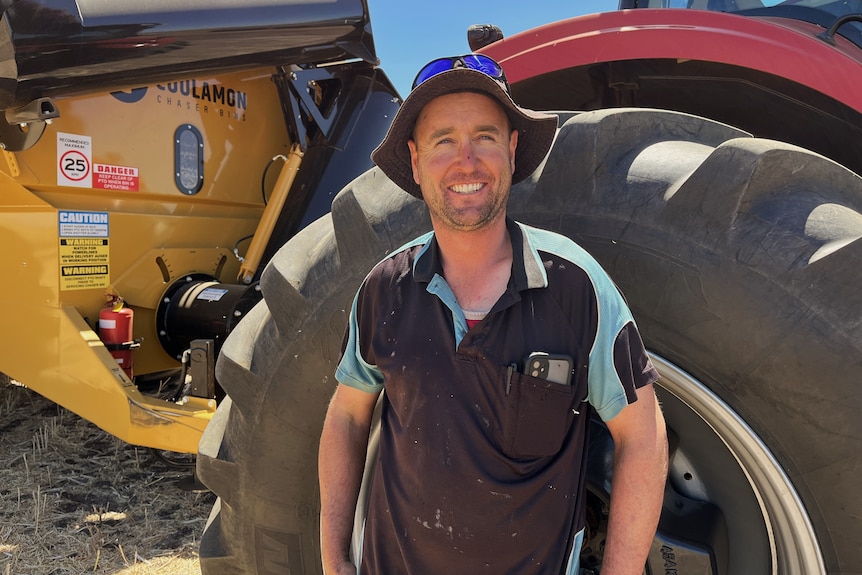 Man standing in front of tractor smiling.
