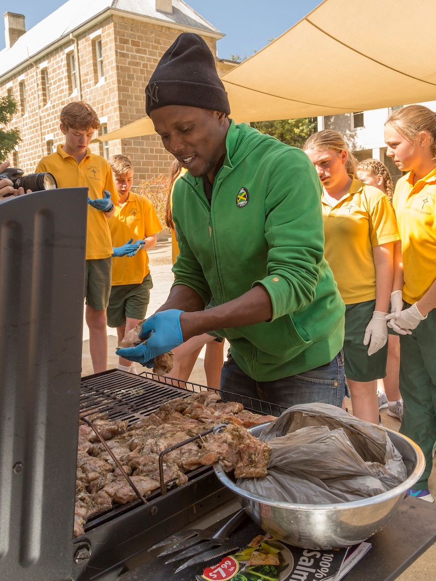 Omar Brown cooks Jamaican jerk chicken with students in Cooma, NSW.
