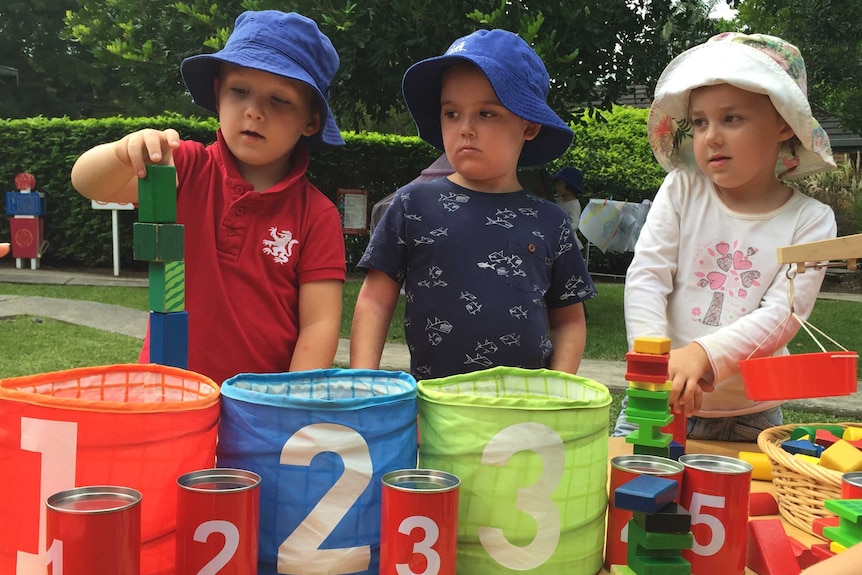Preschoolers count and play with building blocks outside.