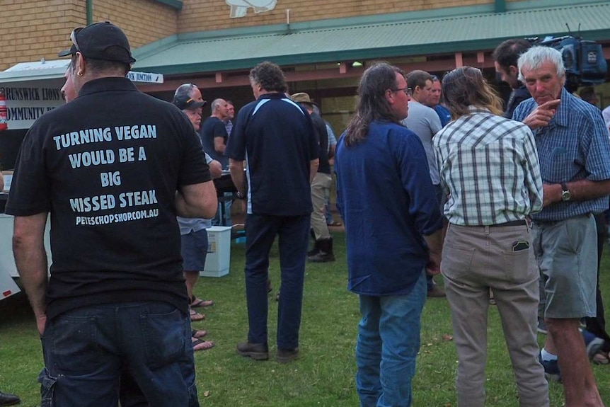 A wide shot showing farmers mingling at a barbeque outside a meeting in Harvey.