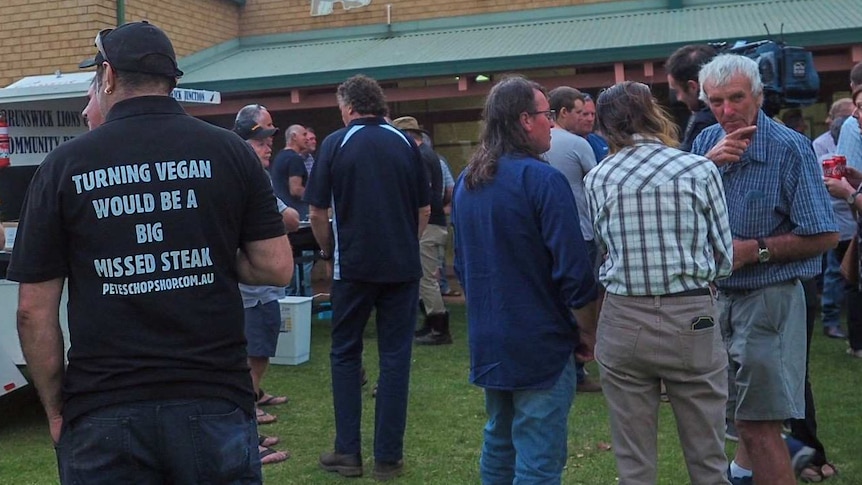 A wide shot showing farmers mingling at a barbeque outside a meeting in Harvey.