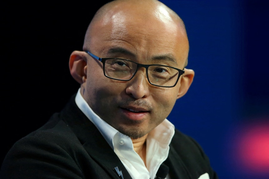 A bald chinese man with square glasses.