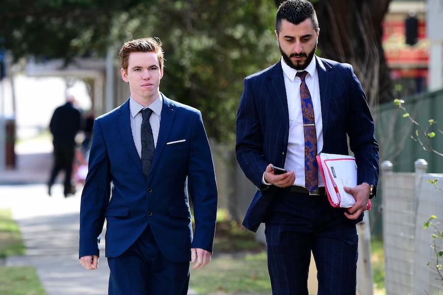 young looking man in suit waking down road with his lawyer