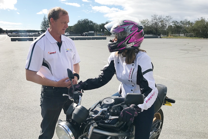 A man speaking to a person wearing a motorbike helmet