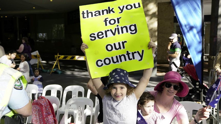 young girl holding sign which read thank you for serving our country