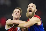 A St Kilda AFL player leans against a Melbourne opponent as they prepare to contest the ball.