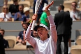Poland's Iga Świątek applauds the crowd clapping her racquet above her head after a win at the French Open.