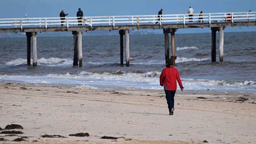A woman walks along Henley Beach near Adelaide.