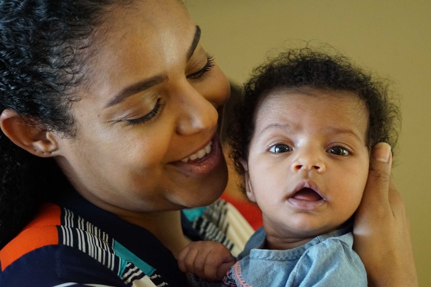 Virginia mum Haben smiles at her daughter Aroura as the newborn stares at the camera.