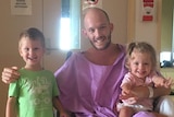 Glenn Dickson sits in a wheelchair surrounded by his kids