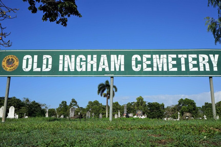 A green sign reading "Old Ingham Cemetery" with graves in the background.