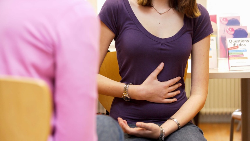 Young woman holding her stomach in a doctor's office