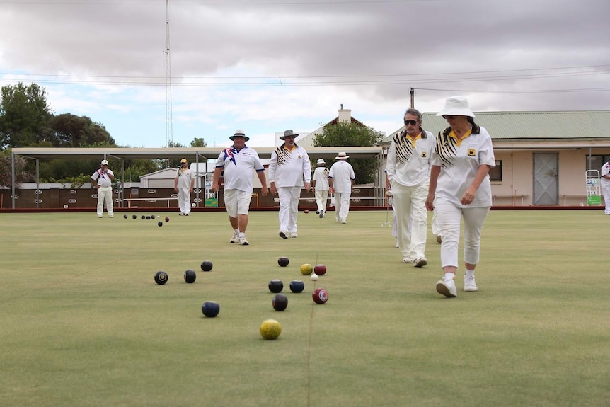 Bowling team members walking across a bowling green.