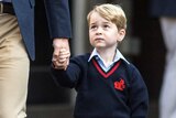 Prince William carries a school bag as he walks hand in hand with Prince George.