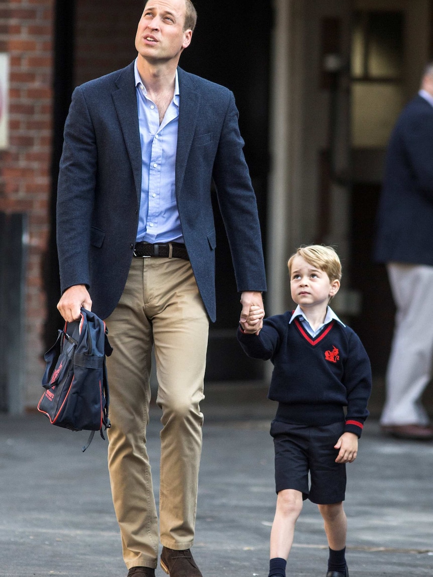 Prince William carries a school bag as he walks hand in hand with Prince George.