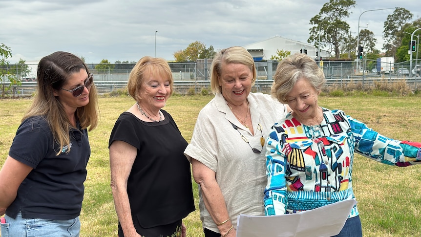Group of women look at plans for homes. 
