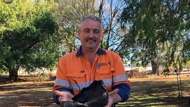 An archaeologist holds up a boot found during works in Toowoomba