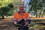 An archaeologist holds up a boot found during works in Toowoomba