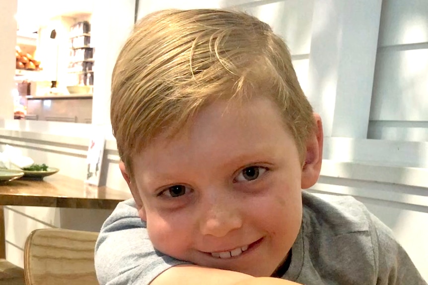 A boy with blonde hair smiles at the camera.