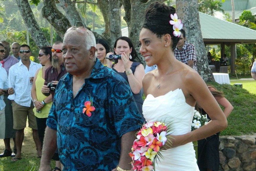 A smiling older man walks next to the bride at an outdoor wedding.