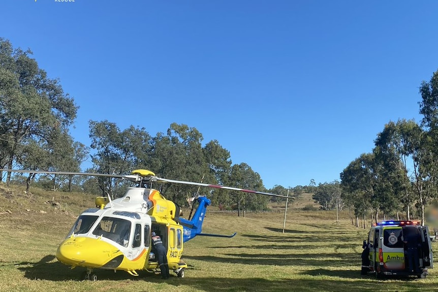 A yellow rescue helicopter and an ambulance in a field.