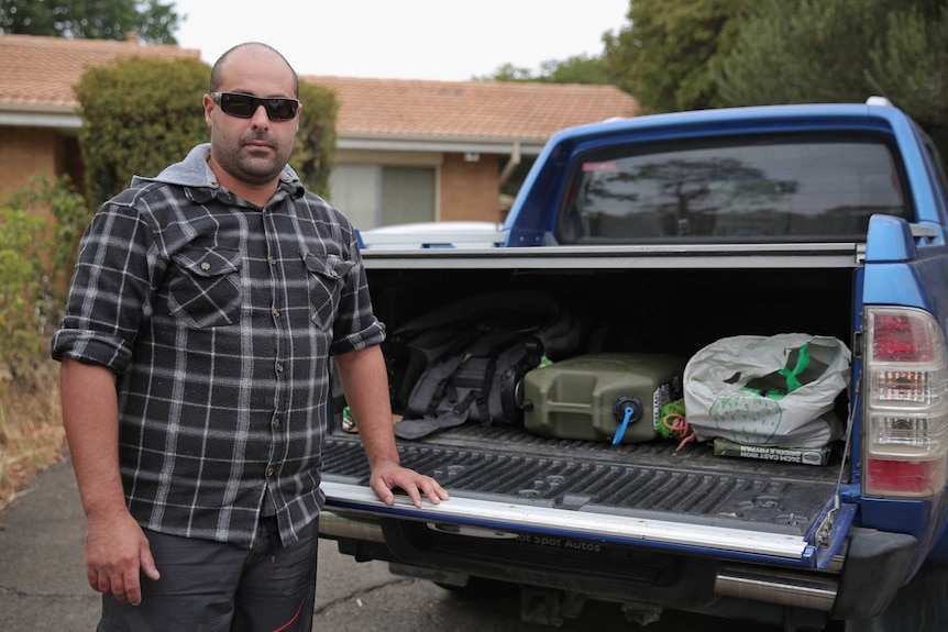 A man stands behind a ute