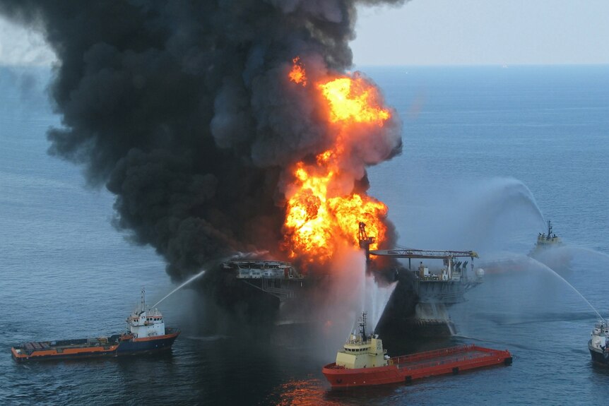 Boats fire water hoses trying to extinguish an oil rig fire.